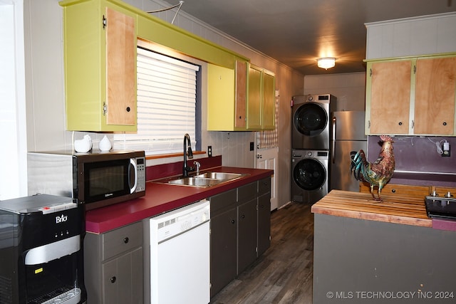 kitchen with stacked washer and dryer, sink, crown molding, stainless steel appliances, and dark hardwood / wood-style flooring