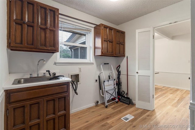 laundry area with cabinets, washer hookup, a textured ceiling, electric dryer hookup, and sink