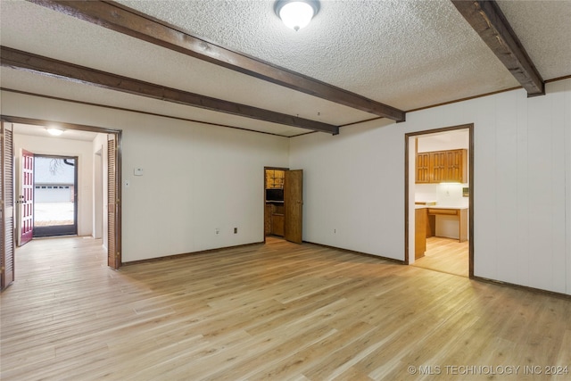 empty room with beam ceiling, a textured ceiling, and light wood-type flooring