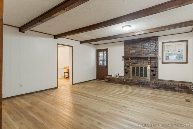 unfurnished living room featuring a fireplace, beam ceiling, a textured ceiling, and light hardwood / wood-style flooring