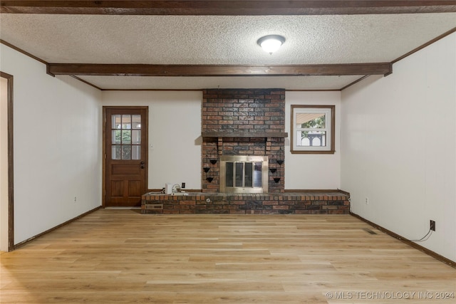 unfurnished living room with light wood-type flooring, beam ceiling, a fireplace, and a textured ceiling