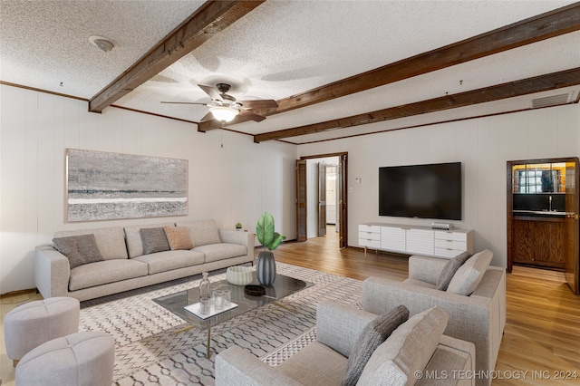 living room with beamed ceiling, a textured ceiling, hardwood / wood-style flooring, and ceiling fan