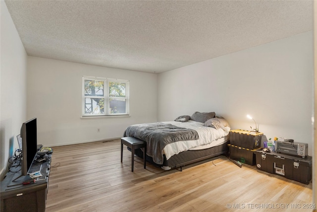 bedroom with a textured ceiling and light wood-type flooring