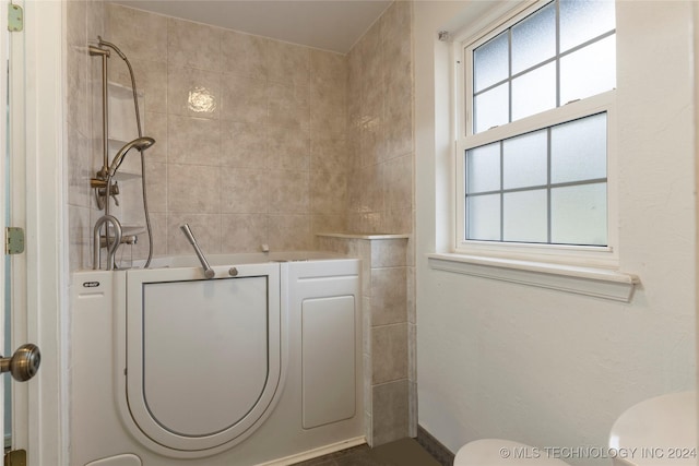 bathroom with toilet, a tub, and a wealth of natural light