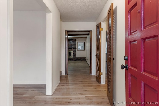 corridor with a textured ceiling and light wood-type flooring