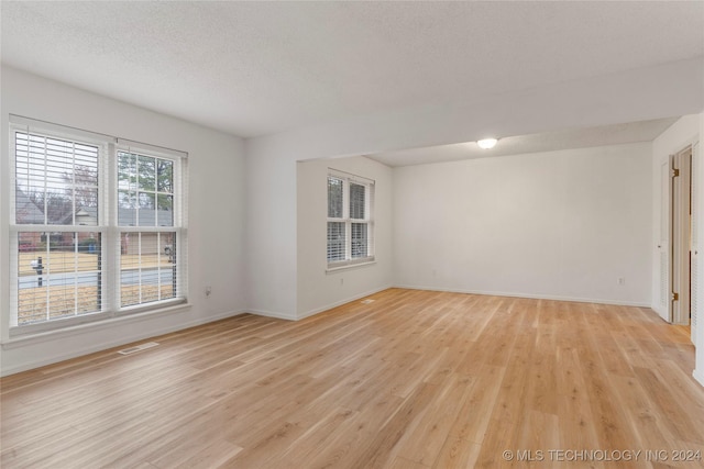 empty room with light hardwood / wood-style flooring and a textured ceiling