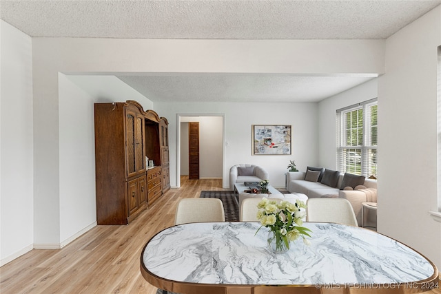 dining area with light hardwood / wood-style floors and a textured ceiling