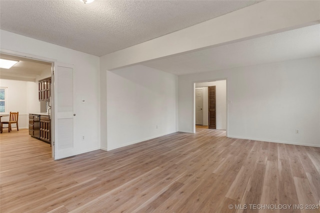 unfurnished room with light wood-type flooring and a textured ceiling