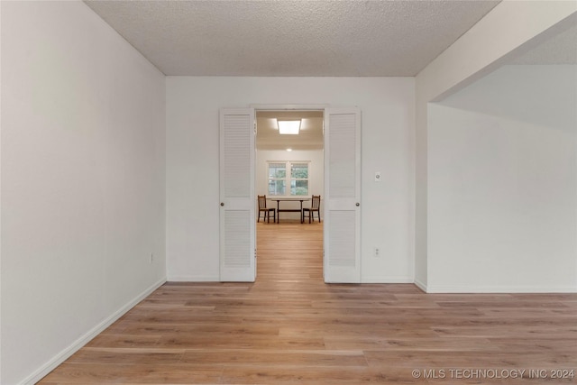 empty room featuring a textured ceiling, baseboards, and wood finished floors