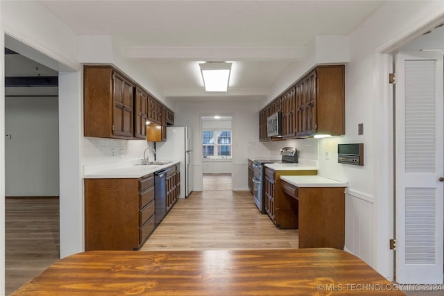 kitchen featuring decorative backsplash, beamed ceiling, light wood-type flooring, and appliances with stainless steel finishes