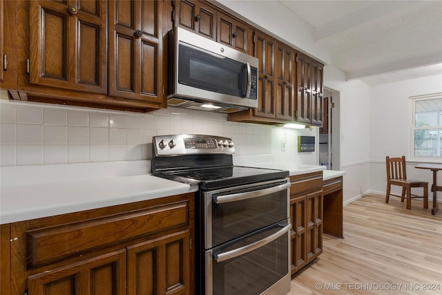 kitchen with backsplash, stainless steel appliances, and light wood-type flooring