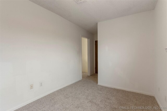 spare room with light carpet and a textured ceiling