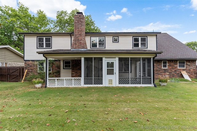 back of house featuring a sunroom, a chimney, brick siding, and a yard