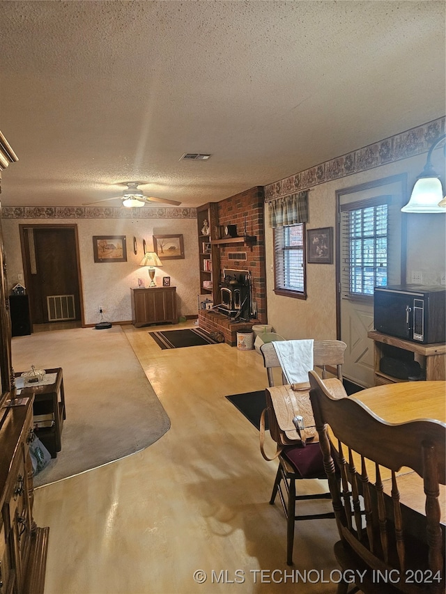 dining space with ceiling fan, a textured ceiling, and a fireplace