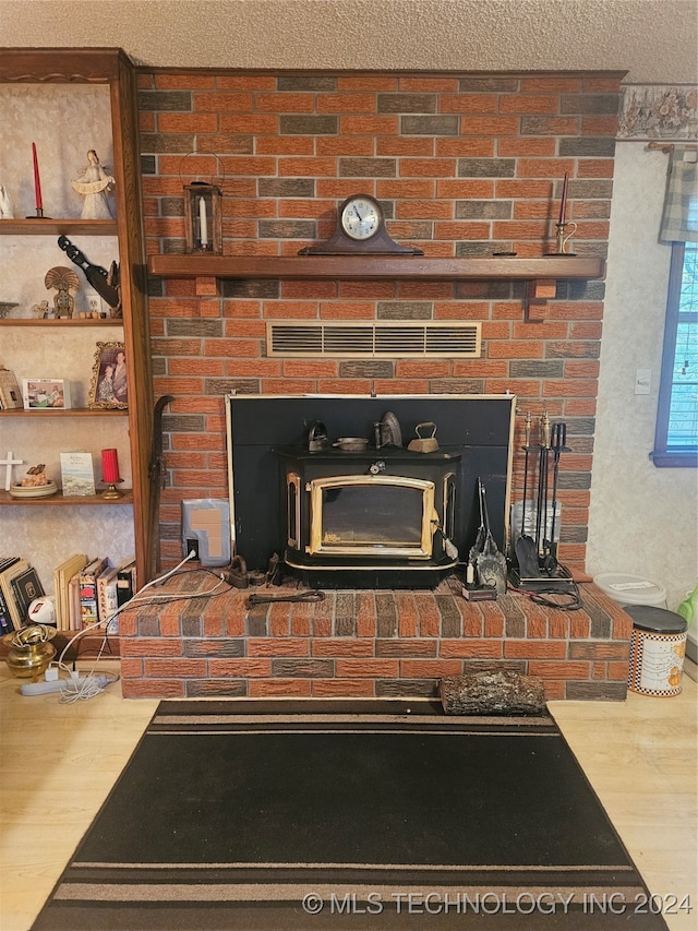 room details featuring a brick fireplace, wood-type flooring, and a textured ceiling