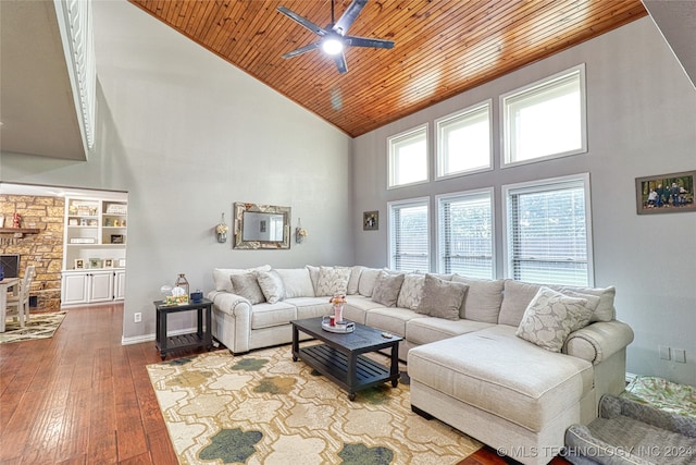 living room featuring wood ceiling, built in shelves, ceiling fan, hardwood / wood-style flooring, and a high ceiling