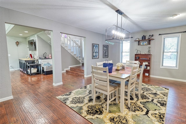 dining space with a textured ceiling, dark hardwood / wood-style flooring, and an inviting chandelier