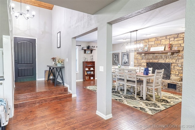 dining space featuring a fireplace, a notable chandelier, and dark wood-type flooring