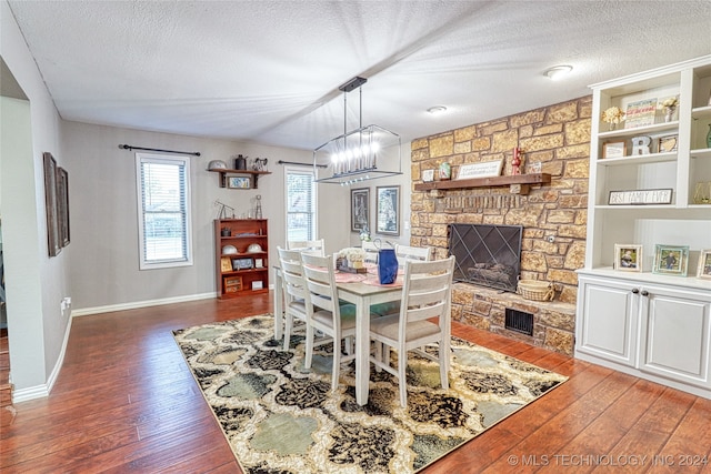 dining area with a fireplace, dark hardwood / wood-style flooring, a textured ceiling, and a chandelier