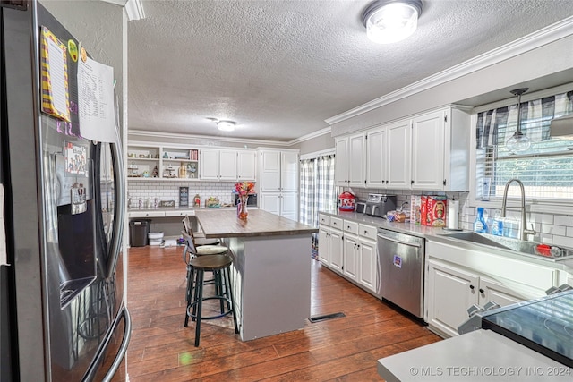 kitchen featuring white cabinets, stainless steel appliances, a kitchen island, and dark wood-type flooring