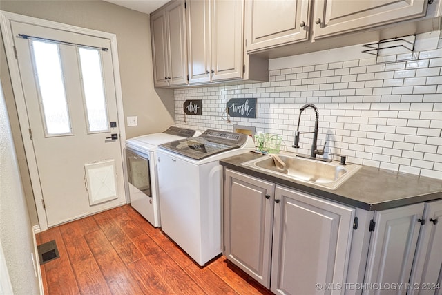 laundry area with sink, washing machine and dryer, dark hardwood / wood-style floors, and cabinets