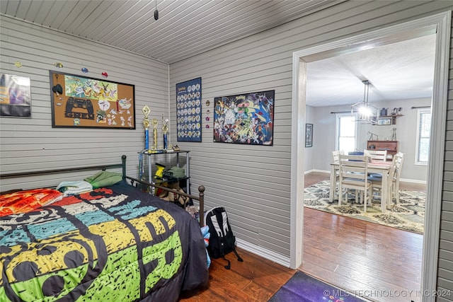 bedroom with wood walls and dark wood-type flooring