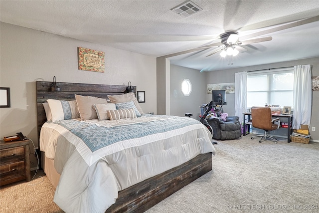 carpeted bedroom featuring ceiling fan and a textured ceiling