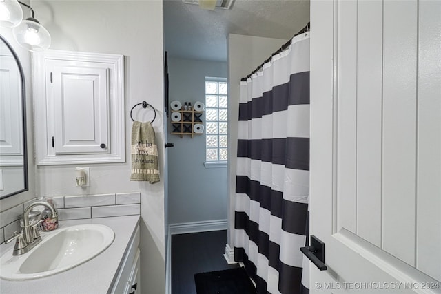 bathroom with curtained shower, vanity, and a textured ceiling