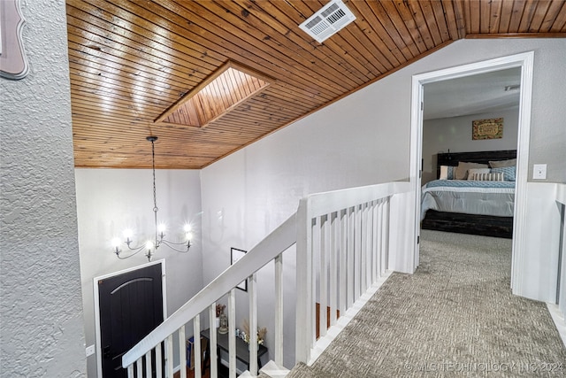 hall with a chandelier, wood ceiling, vaulted ceiling with skylight, and carpet flooring