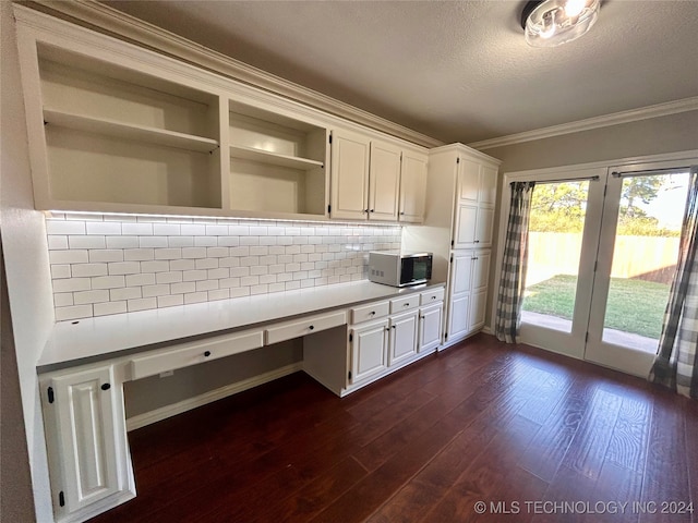 kitchen featuring white cabinetry, tasteful backsplash, built in desk, crown molding, and dark hardwood / wood-style floors