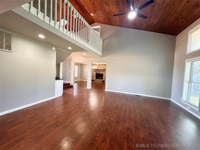 unfurnished living room featuring ceiling fan, wooden ceiling, a stone fireplace, high vaulted ceiling, and dark hardwood / wood-style floors