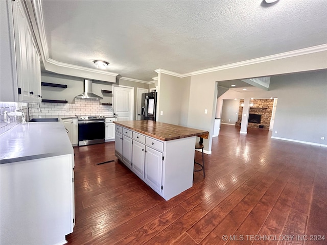 kitchen featuring white cabinetry, black fridge, stainless steel electric range, wall chimney range hood, and a center island