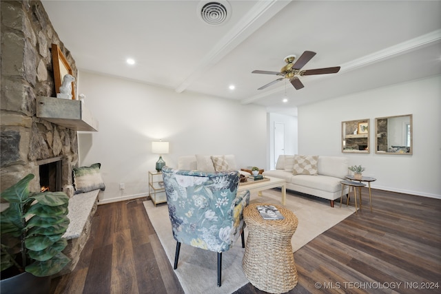 living room featuring dark wood-type flooring, ceiling fan, beamed ceiling, and a fireplace