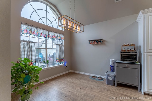 dining space with light wood-type flooring, lofted ceiling, and a chandelier