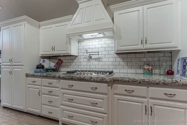 kitchen featuring custom exhaust hood, light wood-type flooring, tasteful backsplash, and white cabinetry