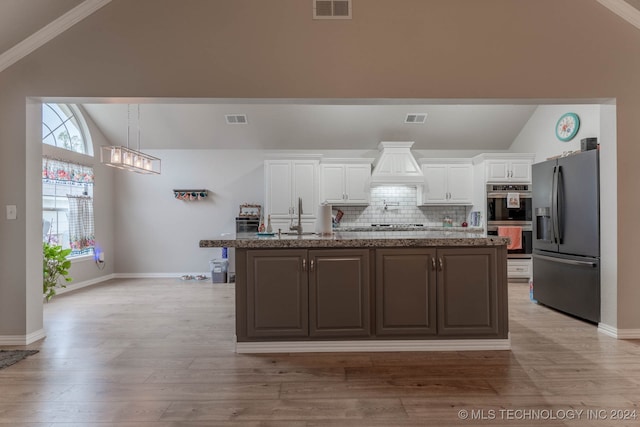 kitchen with white cabinets, stainless steel appliances, light wood-type flooring, and vaulted ceiling