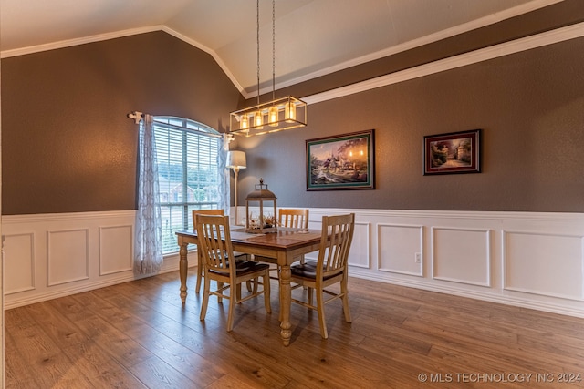 dining space featuring wood-type flooring, ornamental molding, a notable chandelier, and vaulted ceiling