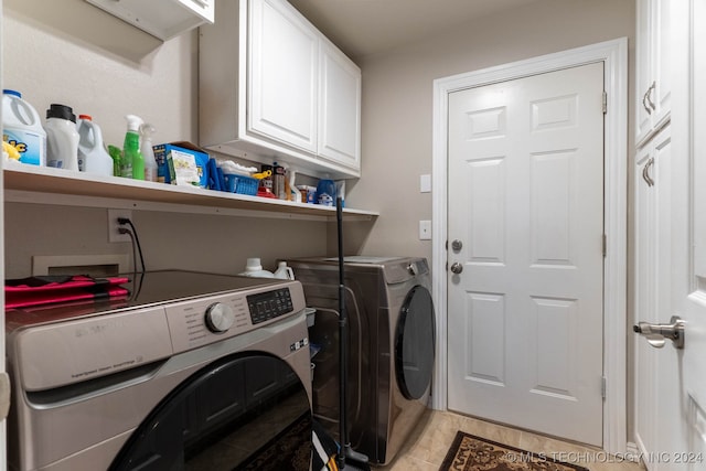 clothes washing area with washer and clothes dryer, cabinets, and light tile patterned flooring