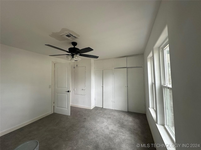 unfurnished bedroom with dark colored carpet, a closet, and ceiling fan