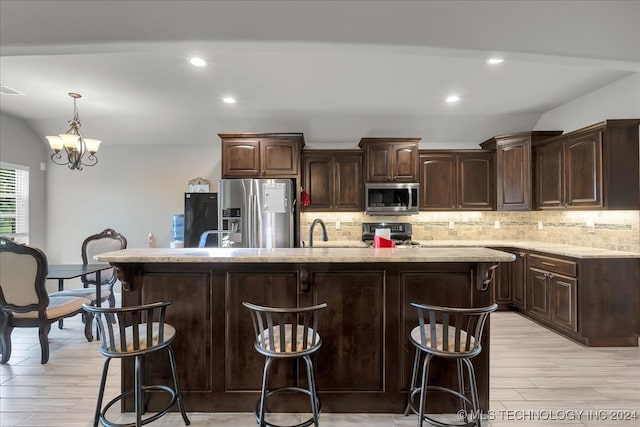 kitchen with dark brown cabinets, a notable chandelier, appliances with stainless steel finishes, and light wood-type flooring