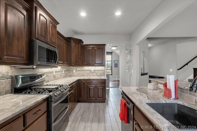 kitchen featuring stainless steel appliances, backsplash, dark brown cabinetry, and sink