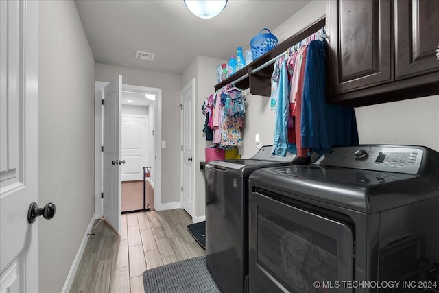 washroom featuring light hardwood / wood-style flooring, cabinets, and washer and dryer