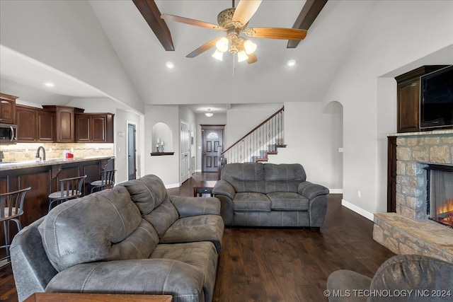 living room with dark wood-type flooring, high vaulted ceiling, a fireplace, ceiling fan, and sink