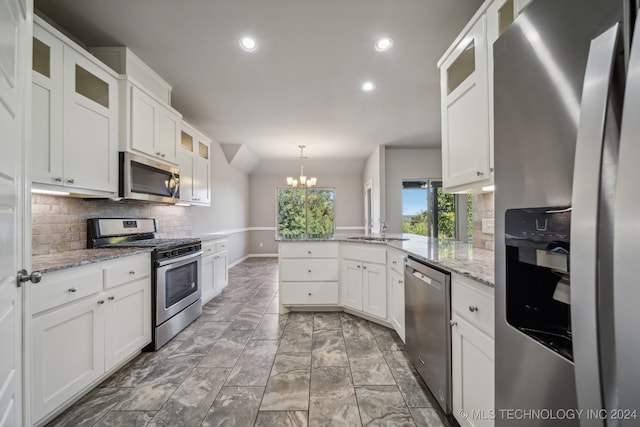 kitchen with a chandelier, white cabinets, kitchen peninsula, appliances with stainless steel finishes, and decorative light fixtures