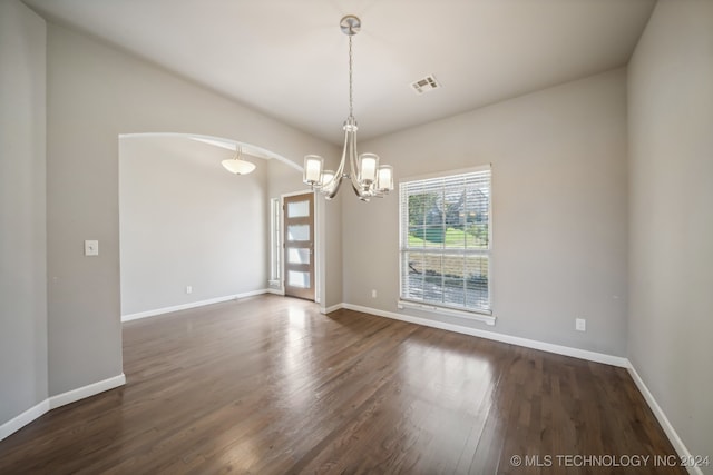 spare room featuring a notable chandelier and dark hardwood / wood-style floors