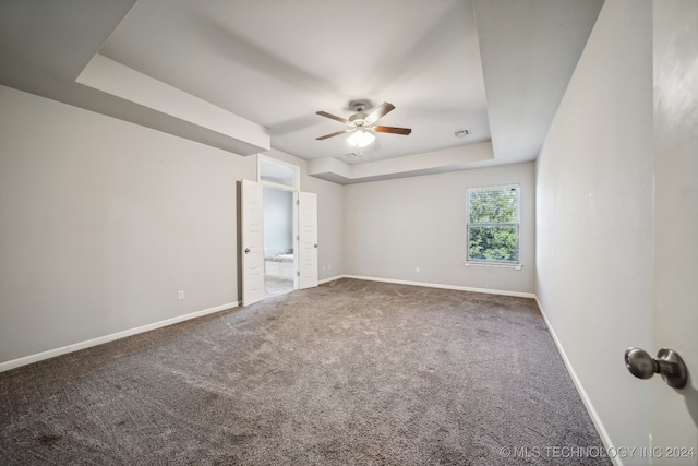 carpeted spare room with a tray ceiling and ceiling fan