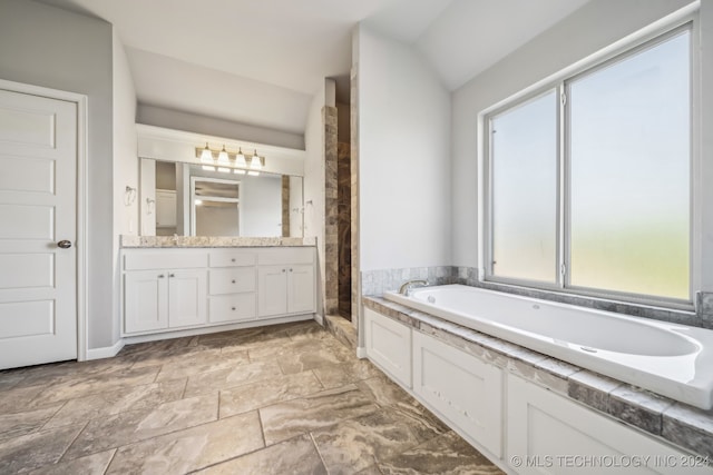 bathroom featuring a tub to relax in, a healthy amount of sunlight, vanity, and vaulted ceiling