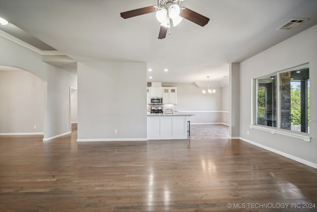 unfurnished living room with ceiling fan with notable chandelier and dark hardwood / wood-style flooring