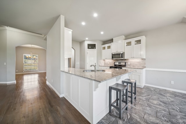 kitchen with light stone counters, sink, white cabinetry, stainless steel appliances, and dark hardwood / wood-style floors