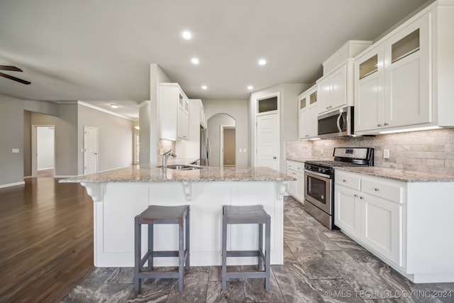 kitchen featuring appliances with stainless steel finishes, a breakfast bar area, dark wood-type flooring, and white cabinets